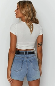 Back view of a white ribbed crop top with drawstring detail and denim shorts with black belt