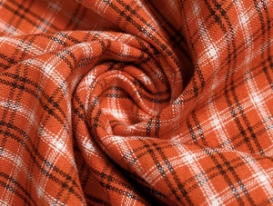 Gros plan du tissu tissé à carreaux orange montrant la texture et la qualité du tissu