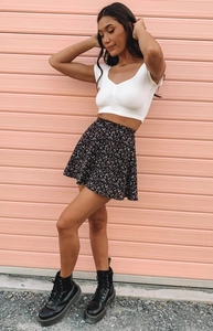 Outdoor shot of floral A-line mini skirt paired with white V-neck cropped top and boots