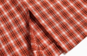 Détail de la mini-jupe à carreaux rouges montrant la fente latérale et la texture du tissu
