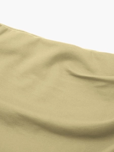Détail du tissu froncé vert olive montrant la texture et les coutures sur la minijupe