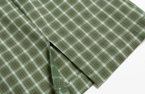 Macro du tissu écossais vert montrant la fente de l'ourlet et la couture de précision