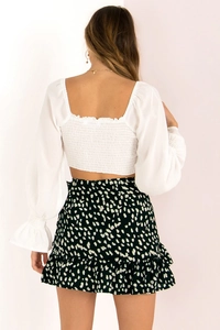 Detail of smocked elastic back on white puff sleeve crop top and polka dot ruffle skirt