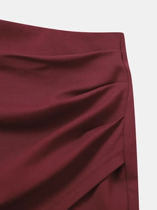 Détail des fronces latérales et de la fente sur une jupe courte taille haute bordeaux