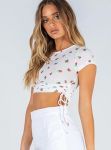 Detailed view of white floral crop top featuring side drawstring and red rose pattern
