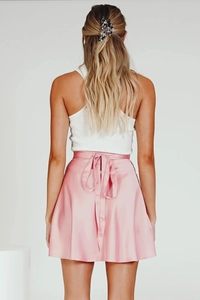 Detail eines rosa Satin-Wickelrocks mit Schleifenbindung und eleganter Textur