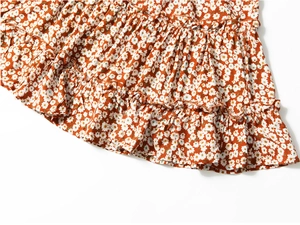 Detail of orange floral skirt with tiered ruffles and white daisy print pattern