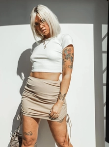 Detail of drawstring side ruching on a khaki ribbed knit mini skirt with white crop top
