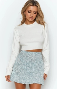 Detail of high-waisted floral chiffon skirt paired with a white knit long-sleeve top