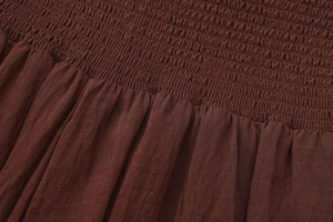 Macro view of smocked waist detail and textured fabric on dark brown A-line skirt