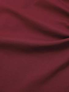 Gros plan sur le tissu plissé irrégulier rouge vin avec coutures fines sur la jupe