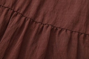 Macro detail of high-waist pleated smocking and deep reddish brown cotton fabric texture