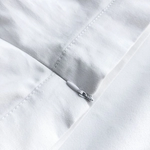 Detail view of white fabric showing smooth invisible zipper and clean stitching craftsmanship