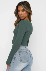 Detail of dark green ribbed long sleeve top paired with high-waisted washed blue jeans