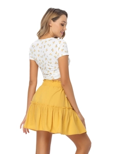 Rear view detail of a floral crop top and yellow ruffled mini skirt with high-waist pleats