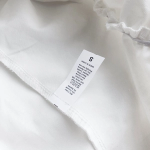 Detailed fabric care label showing 80% cotton blend material on white ruffled skirt