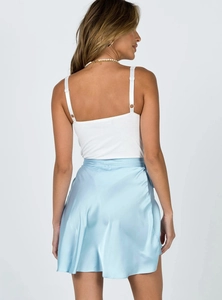 Rückansicht eines weißen Camisole-Tops und hellblauem Satin-Wickelrock am Model