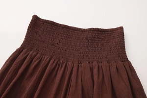 Detailed close-up of smocked high waist design and elastic waistline on brown A-line skirt