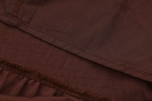 Close-up of the professional stitching and hem details on brown woven skirt fabric