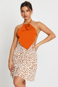 Detail of orange satin halter top with open back and boho print ruffle layered skirt