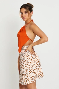 Detail view of orange satin halter top and spotted layered skirt on a model in studio