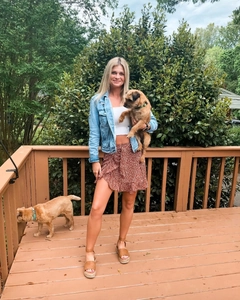Outdoor lifestyle view of a floral ruffle mini skirt styled with a blue denim jacket