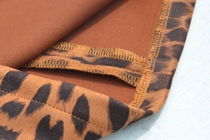 Gros plan sur la couture overlock et la texture du daim d'une jupe courte léopard