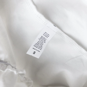 Close-up of garment care label on white high waist skirt with 80% cotton material detail