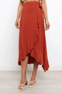 Detail view of deep orange wrap skirt with ruffled asymmetrical hem and waist tie closure