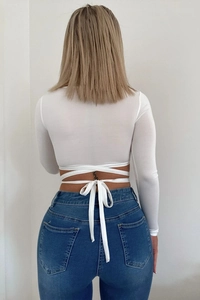 Detailed back view of white long sleeve crop top with criss-cross lace-up bow design