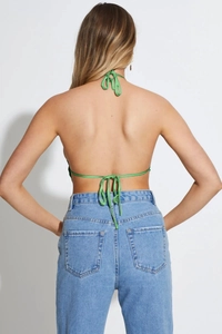 Detail of green halter neck tie top and light blue high waist denim jeans back view