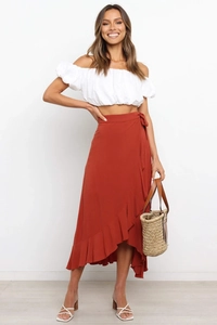 Detail of rust red wrap skirt with ruffled hem paired with white puff sleeve crop top