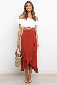 Detail of rust wrap skirt with waist tie and asymmetrical ruffle hem in chiffon fabric