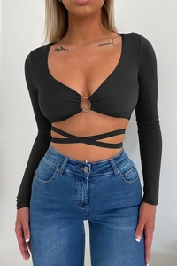 Detail of black long sleeve crop top with metal ring buckle and waist cross wrap straps