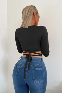 Detail of crop top back featuring multiple long strap ties wrapped and knotted in a bow