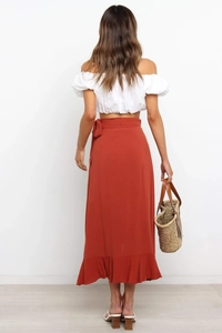 Rear view of a chic white off-the-shoulder crop top and rust red ruffled wrap skirt set