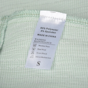 Detail shot of the care label and fabric texture on a green checkered ruffle skirt