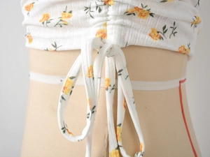 Detailed view of white floral print t-shirt featuring drawstring textured fabric and ruffles