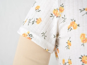 Macro detail of ribbed knit sleeve with yellow floral print and precise stitching