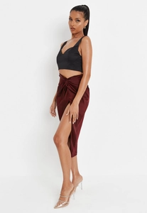 Detail of the high slit wine red satin skirt with twist knot and glossy silk texture
