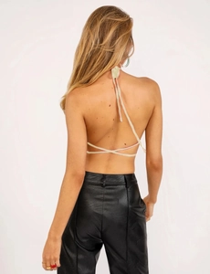 Detail of cross-tie backless halter top in light beige paired with black faux leather pants