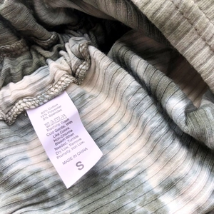Detail of ribbed knit fabric texture with green tie-dye pattern and S size care label