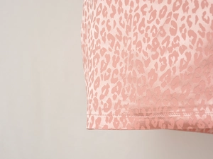 Détail macro du tissu satiné rose clair à motif léopard avec double couture précise