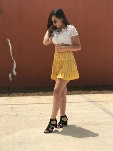 Detail of high waisted yellow floral mini skirt with white lace off-shoulder crop top outfit