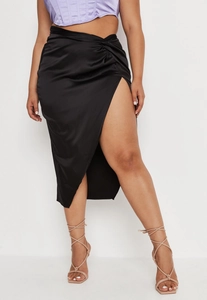 Detailed view of black satin midi skirt with elegant twist knot and high slit design