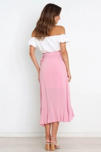 Back view of woman in white off-shoulder top and pink high waist ruffle wrap midi skirt
