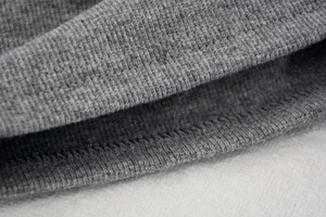 Detailed close-up showing precision double-needle stitching on gray knit elastic fabric