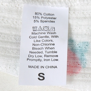 Detailed fabric care label on a white printed t-shirt showing cotton blend material size S
