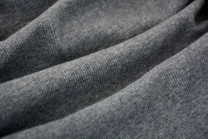 Macro texture view of dark grey knitted ribbed fabric with elastic folded details