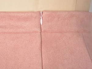 Détail de la taille d'une jupe en daim rose avec une fermeture à glissière invisible